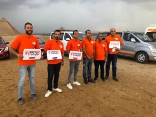our drivers and employees holding our sign with our cars in front of the pyramids