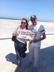 guests holding our sign in front of sea